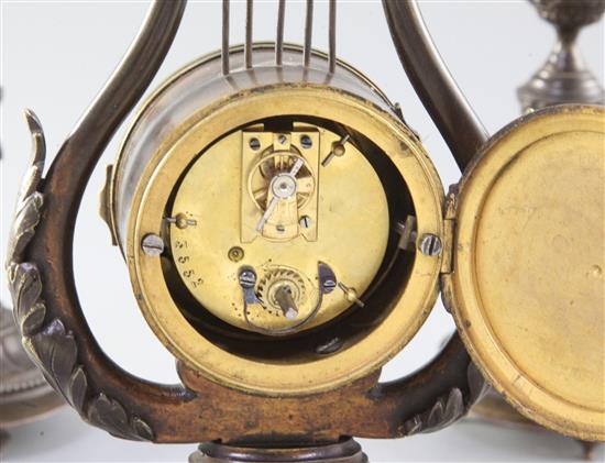 An early 20th century French patinated bronze garniture, clock 21.5cm. candlesticks 15cm.